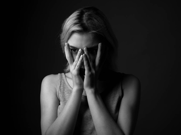 Portrait of sad young woman with hands on the face. Black and white - Фото, изображение