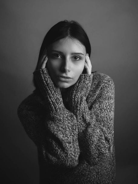 Young woman in sweater on gray background. Black and white - Valokuva, kuva