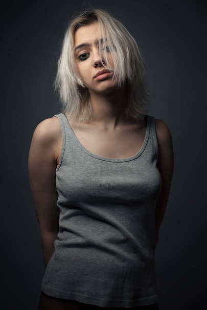 Young blonde woman with smeared make up on gray background - Fotoğraf, Görsel