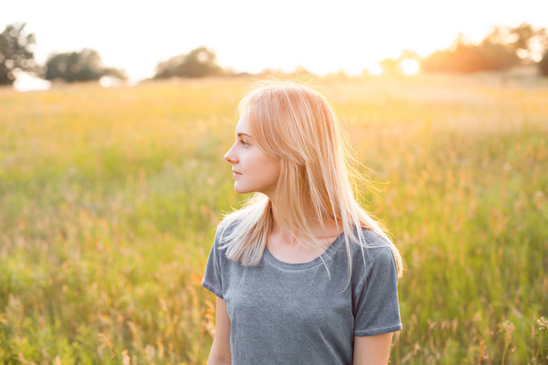 Portrait of young woman on the field at evening - Foto, Imagen