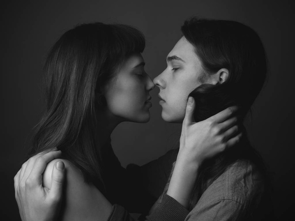 A young man and a young woman kissing. Black and white - Zdjęcie, obraz