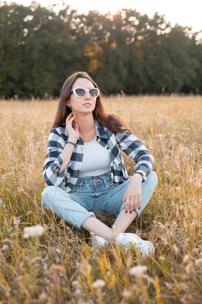 Young woman in sunglasses sitting on the lawn - Photo, Image