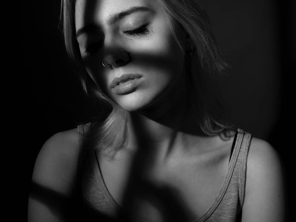 Portrait of sad girl in deep shadows. Black and white. Low key - Fotografie, Obrázek