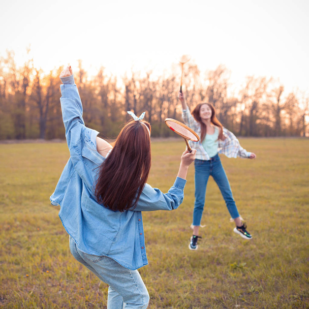 Two young women play badminton outdoors at sunset. Best friends - Фото, зображення