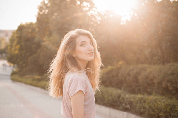 Young woman with long hair walking down the street under sunlight - Foto, Bild
