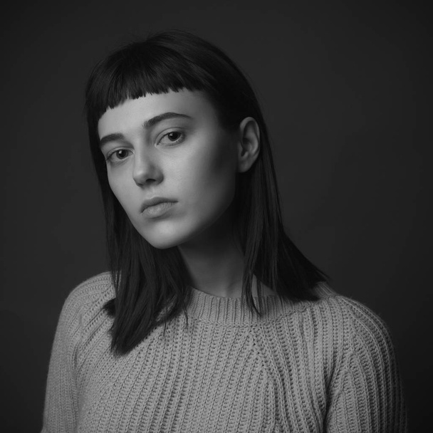 Portrait of young woman in sweater on black background. Black and white - Φωτογραφία, εικόνα