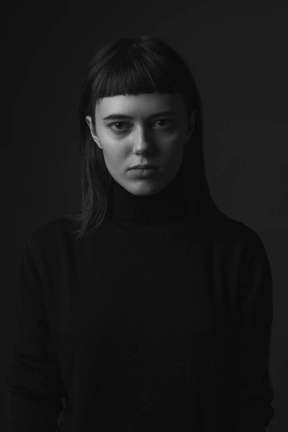Portrait of serious young woman. Low key. Black and white - Фото, изображение