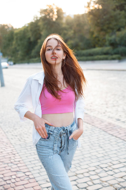 Attractive young woman with long hair walking on the street under daylight. - Foto, afbeelding