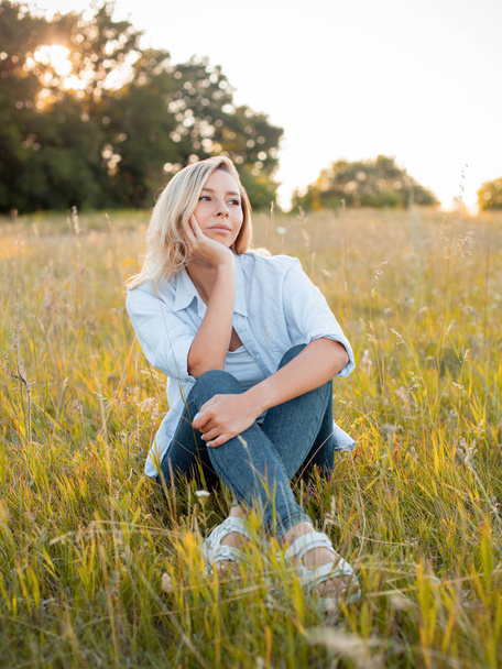 Young woman sitting on the green field under sunlight - Φωτογραφία, εικόνα