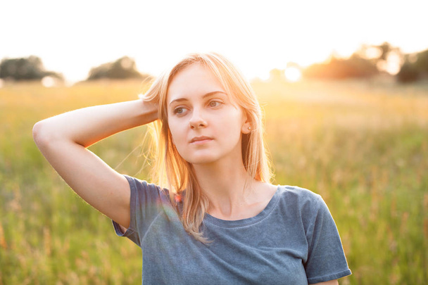 Portrait of young woman on field at evening - Foto, imagen