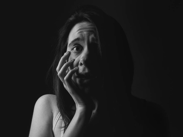 Portrait of scared young woman. Low key. Black and white - Photo, Image