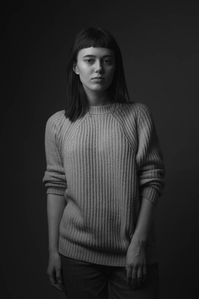 Portrait of young woman in sweater on black background. Black and white - Fotografie, Obrázek
