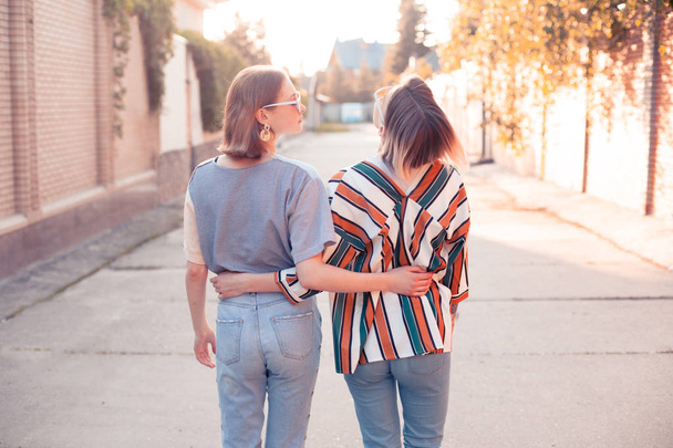 Two fashionable young women walking down the street. Back - Fotoğraf, Görsel