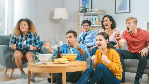 At Home Diverse Group of Sports Fans Sitting on a Couch Watching Important Sports Game Match on TV, They Cheer for the Team at a Very Tense Moment. Cozy Room with Snacks and Drinks. - Φωτογραφία, εικόνα