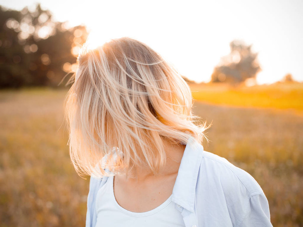 Porträt einer blonden jungen Frau im Freien bei Sonnenuntergang. Haare hautnah - Foto, Bild