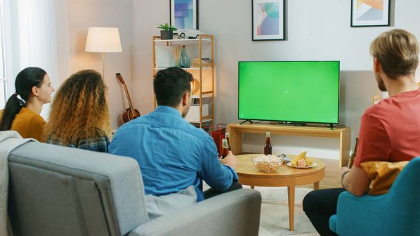 Happy Friends Sitting At Home Watching Green Chroma Key Screen, Relaxing on a Couch. Watching Sports Match, News, Sitcom TV Show or a Movie. - Foto, afbeelding