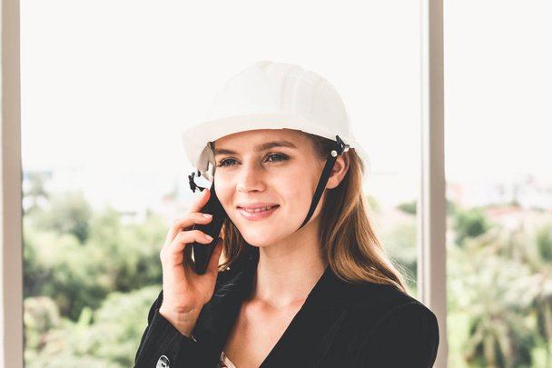 Female engineer on phone and speaking with team. - Фото, зображення