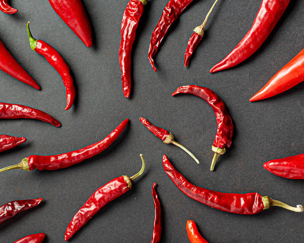 A lot of red pepper and peppercorns on a black background. View from above. - Photo, Image