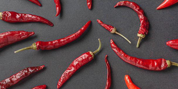 A lot of red pepper and peppercorns on a black background. View from above. - 写真・画像