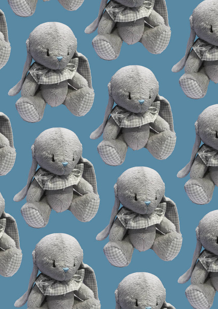 Gray cute teddy rabbit isolated on blue background. Teddy rabbit Plush pattern. Children's concept. Composition of toys. Flat lay, top view. Copy space - 写真・画像