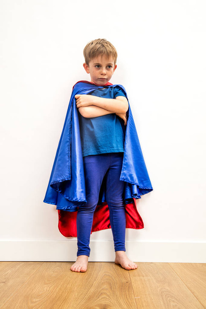 Verlorenes kleines Superheldenkind mit verschränkten Armen beim Nachdenken über Traurigkeit - Foto, Bild
