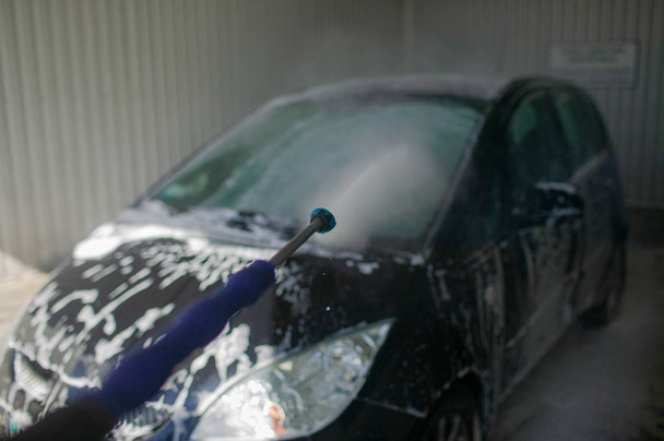 l'auto rossa si sta lavando nel sapone. Lavaggio auto nera da acqua ad alta pressione. Primo piano autolavaggio
. - Foto, immagini