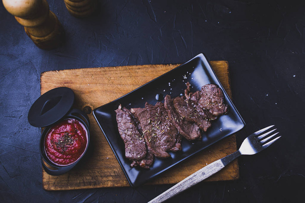 Steak de boeuf coupé en lanières avec sauce tomate sur bois
. - Photo, image