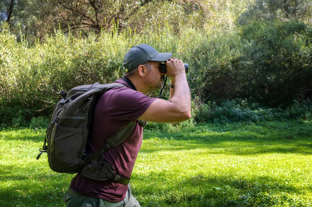 Άνθρωπος εξερευνητής στο δάσος, σαρώνει τον ορίζοντα με κιάλια - Φωτογραφία, εικόνα