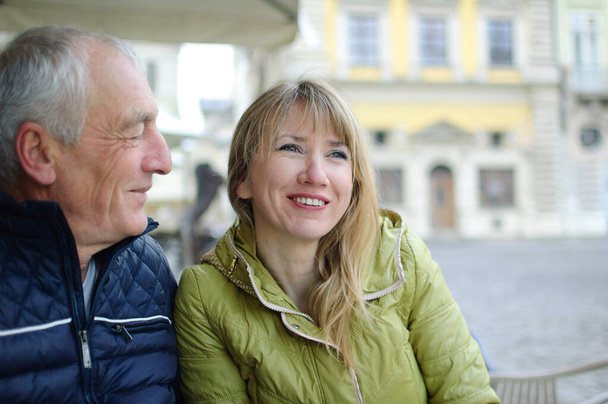 Bello uomo anziano sta abbracciando la sua giovane moglie bionda trascorrere del tempo insieme all'aperto nella città antica durante l'inizio della primavera o l'autunno
. - Foto, immagini