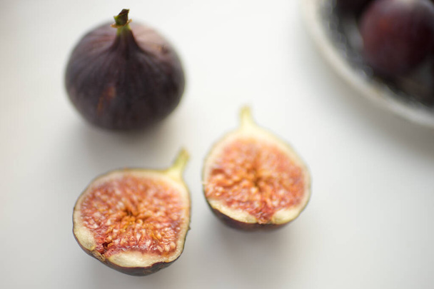 One whole fig and the second cut in half on a white table - Photo, Image