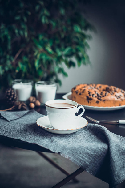 Cup of coffee or cocoa, cake, candles and natural cones, nuts decor on the dark table. Cozy atmosphere at home. Morning in noir nordic style. Hygge concept. Soft selective focus. Vertical. Copy space. - Photo, image