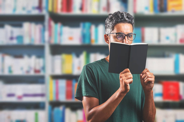 homme portant des lunettes lisant un livre à la bibliothèque
 - Photo, image