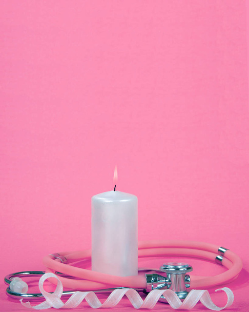 Consciência do câncer de mama, Vela rosa claro ardente com estetoscópio envolto em torno dele fita rosa com loop em fundo rosa texturizado, apresentação vertical com grande espaço de cópia acima
 - Foto, Imagem