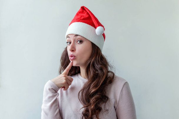 Krásná dívka v červeném Santa Clause Hat je izolovaná na bílém pozadí - Fotografie, Obrázek