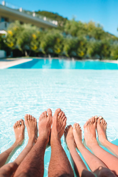 Close up of four peoples legs by pool side - Photo, Image