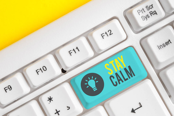 Conceptual hand writing showing Stay Calm. Business photo showcasing Maintain in a state of motion smoothly even under pressure White pc keyboard with note paper above the white background. - Photo, Image