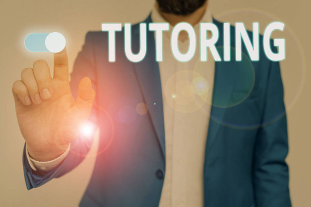 Conceptual hand writing showing Tutoring. Business photo showcasing An act of a demonstrating employed to administer knowledge to someone Male wear formal suit presenting presentation smart device. - Photo, Image