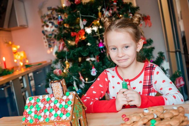 Kislányok, hogy karácsonyi mézeskalács ház kandalló díszített nappaliban. - Fotó, kép