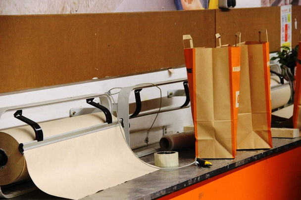 грубая оберточная бумага, клейкая лента, бумажные ножи и пакеты для покупок, интерьер в оранжевых тонах
 - Фото, изображение