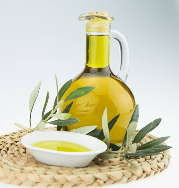 Oliiviöljy Pullo ja kulho lautasen oliivipuun oksa. Neitsytoliiviöljy. Luonnollinen oliiviöljy, terveellinen ruoka. Luonnollista välimeren ruokaa. Leipädippaus
. - Valokuva, kuva