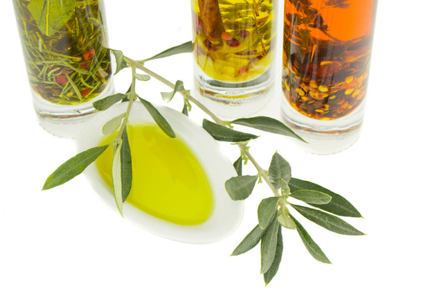Olivenöl-Teller mit Olivenzweig und Gewürzen und Kräutern im Hintergrund. natives Olivenöl. natürliches Olivenöl, gesunde Ernährung. - Foto, Bild