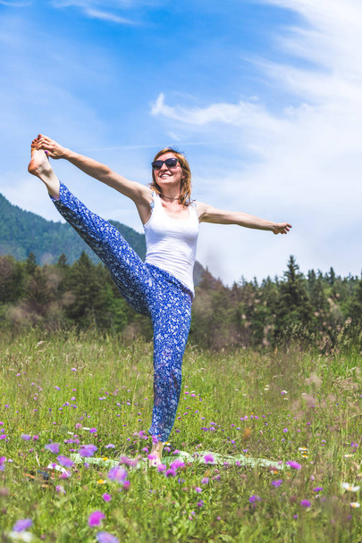 young woman doing yoga on summer background - Foto, afbeelding