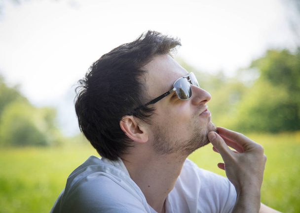 Man in sunglasses relaxing on green grass outdoors - Foto, Bild