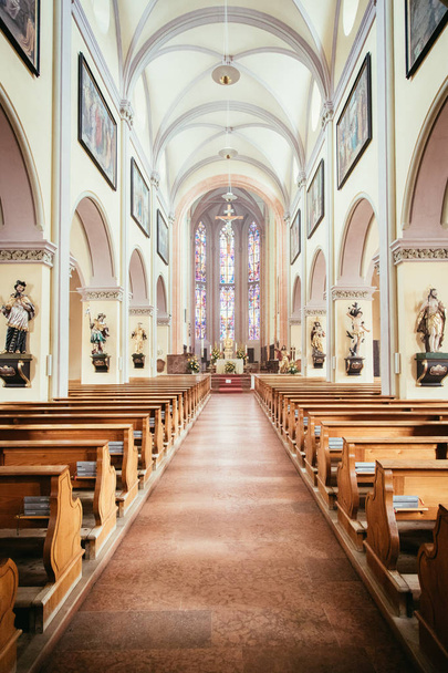 Inside of a large, modern church with pews and cross visible  - Photo, image