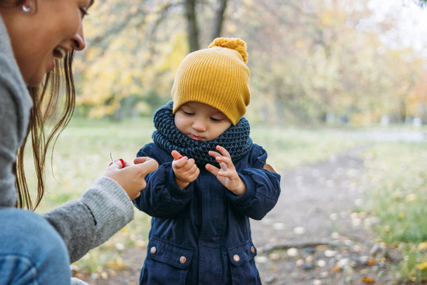 Cute baby boy in fashionable casual clothes explores world with mother in autumn nature park - Foto, Imagem