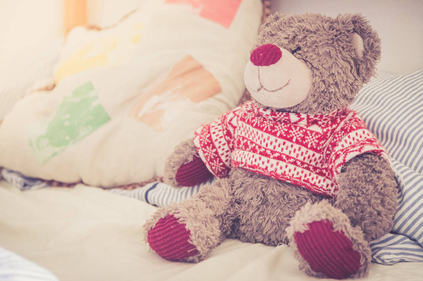 Cute teddy bear toy is sitting in the bed, wakeup at morning, sunlight - Photo, image