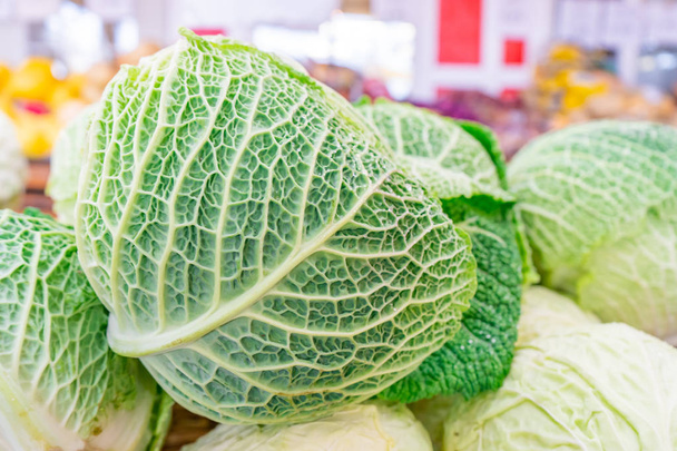 Крупный план савойской капусты (зеленый сорт капусты), с толстыми, текстурированными листовыми венами, которые продаются на фермерском рынке
. - Фото, изображение