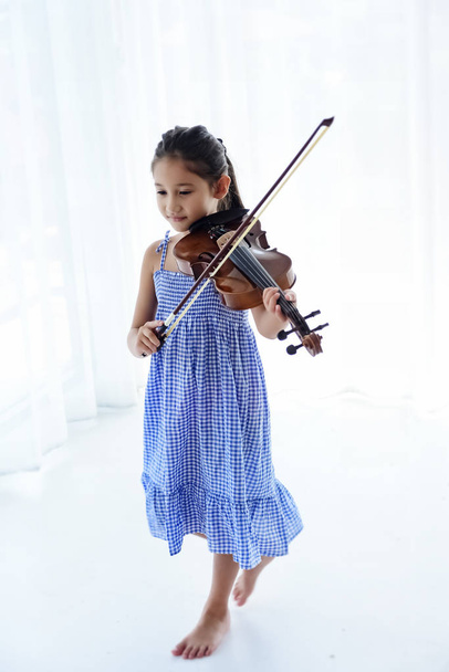 El pequeño gril tocando el violín con sensación de felicidad, luz borrosa alrededor
 - Foto, imagen