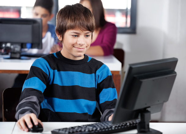 Boy Smiling While Using Computer In Classroom - Photo, image