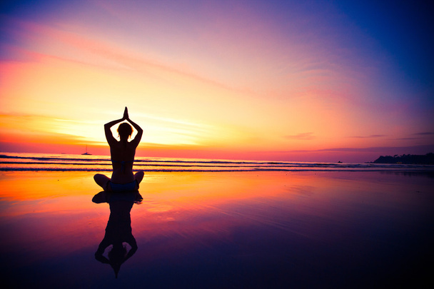 Йога жінка, що сидить на узбережжі моря, на заході сонця - Фото, зображення